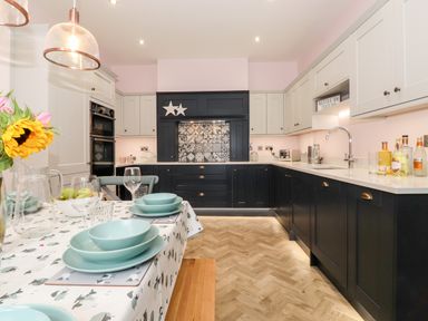A kitchen with black and white cabinets a patterned tile backsplash and a dining table with blue dishes at Eller Close House in Grasmere