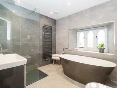 A bathroom with a freestanding bathtub a walk in shower sink and window at Eller Close House in Grasmere