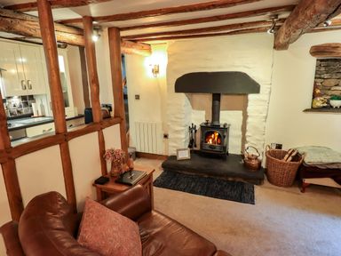 A living room with a fireplace and sofa at Fellside Cottage in Bowness-On-Windermere