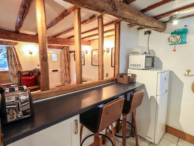 A kitchen with bar stools and appliances at Fellside Cottage in Bowness-On-Windermere