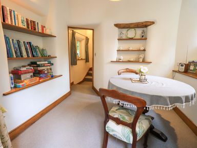 A dining room with bookshelves and a table at Fellside Cottage in Bowness-On-Windermere