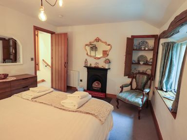 A bedroom with a bed and armchair at Fellside Cottage in Bowness-On-Windermere
