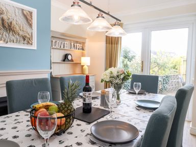 A dining area with a table set with plates wine glasses and a fruit basket at Pooley Howe in Keswick