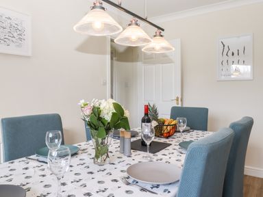A dining room with a table set with plates glasses flowers and fruit bowl at Pooley Howe in Keswick