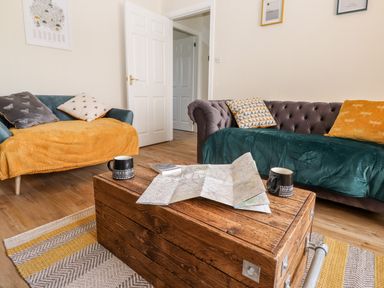 A living room with two sofas a wooden coffee table with a map and mugs at Pooley Howe in Keswick