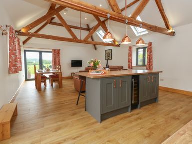 An open plan kitchen and dining area with wooden beams and a kitchen island at Swallows Nest in Puxey near Sturminster Newton