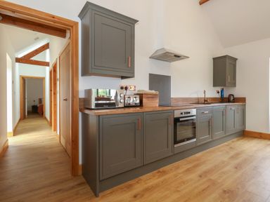 A kitchen with grey cabinets wooden countertops and floor at Swallows Nest in Puxey near Sturminster Newton
