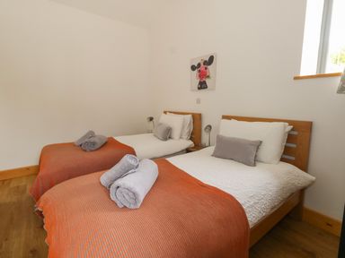 A bedroom with two single beds with orange blankets and rolled towels at Swallows Nest in Puxey near Sturminster Newton