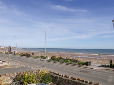 A view of the sea and beach with people walking at Ocean View Apartment in Colwyn Bay