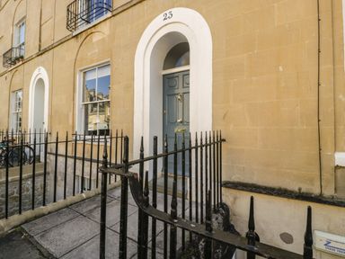 An exterior view of a building entrance with a blue door numbered 23 and black metal railings at 23 Daniel Street in Bath