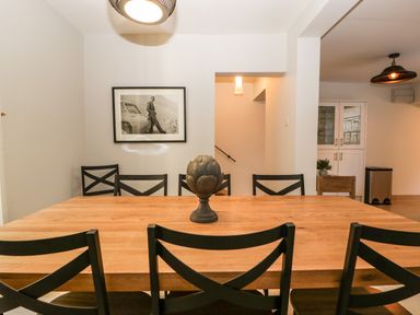 A dining room with a wooden table and black chairs a decorative item on the table and a black and white framed photo on the wall at 23 Daniel Street in Bath