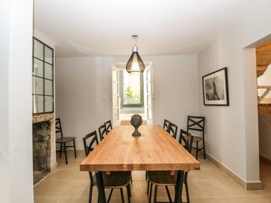 A dining room with a wooden table and black chairs with a pendant light and a window at 23 Daniel Street in Bath