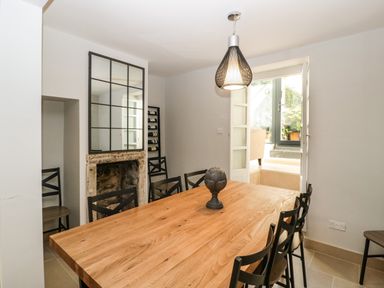 A dining room with a wooden table and black chairs a large mirror above a fireplace and a pendant light at 23 Daniel Street in Bath