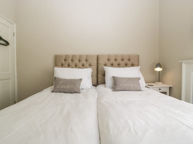 A bedroom with two single beds with tufted headboards and pillows saying love at 23 Daniel Street in Bath