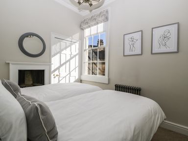 A bedroom with two beds pillows fireplace window and two framed line art drawings at 23 Daniel Street Bath