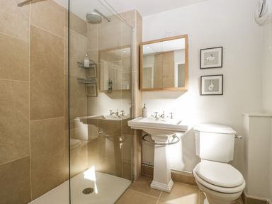 A bathroom with a walk-in shower a pedestal sink a toilet and framed pictures at 23 Daniel Street in Bath