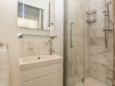 A bathroom with a sink and faucet next to a glass-enclosed shower at 23 Daniel Street in Bath