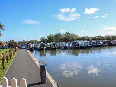 A pathway beside a water canal with several boats docked and a sign reading private berth holders only at The Wren in Wem