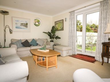 A living room with sofas cushions coffee table artwork and a window with curtains at Creekside House in Fowey