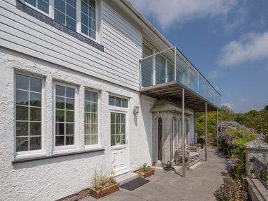 Exterior view of a white house with windows door balcony and garden plants at Creekside House in Fowey