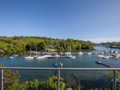 A view of boats docked in a river with green hills and trees in the background at Creekside House in Fowey