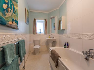 A bathroom with a bathtub sink toilet and towel rack at Creekside House in Fowey