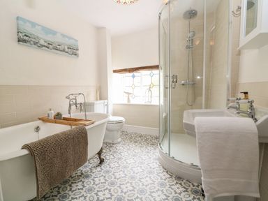 A bathroom with a freestanding bathtub a walk-in shower a toilet and a sink with towels at Tuesday Cottage in Bourton-On-The-Water