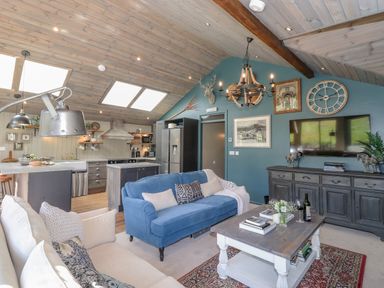 An open plan living room and kitchen with sofas and a wooden coffee table at The Owls Shack in Kendal