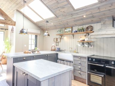 A kitchen with an island counter black oven hanging lights and shelves with decorative items at The Owl's Shack in Kendal