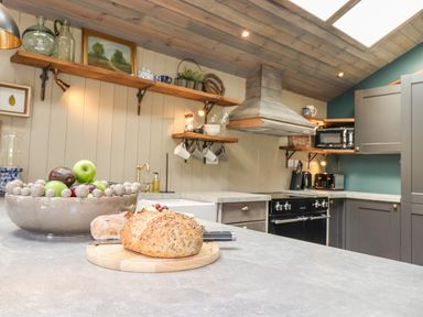 A kitchen with bread on a cutting board and fruit bowl on countertop at The Owl's Shack in Kendal