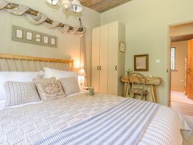 A bedroom with a bed pillows a bedside lamp a wardrobe a mirror and a small wooden desk with a chair at The Owl's Shack in Kendal