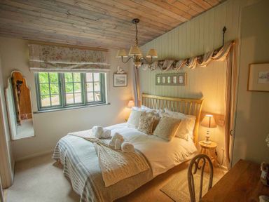A bedroom with a wooden bed frame and bedside lamps at The Owl's Shack in Kendal