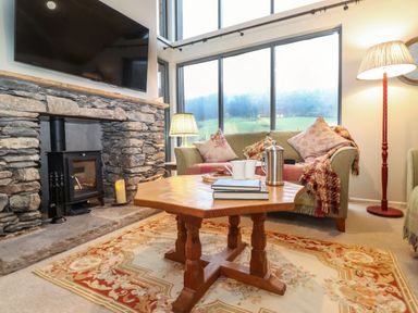 A living room with a stone fireplace and a wooden coffee table at The Badger's Shack in Garnett Bridge Longsleddale Near Kendal