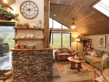 A living room with two sofas a wooden coffee table and large windows overlooking hills at The Badgers Shack in Garnett Bridge Longsleddale Near Kendal