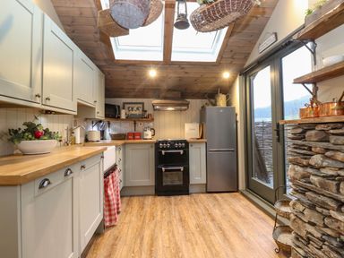 A kitchen with wooden countertops a stove a refrigerator skylights and glass doors at The Badger's Shack in Garnett Bridge Longsleddale Near Kendal