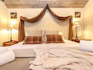 A bedroom with a double bed brown plaid pillows and curtains bedside tables with lamps and folded towels at The Badgers Shack in Garnett Bridge Longsleddale Near Kendal