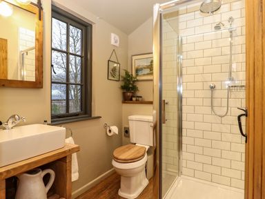A bathroom with a shower enclosure toilet sink wooden framed mirror and window at The Badger's Shack in Garnett Bridge Longsleddale Near Kendal