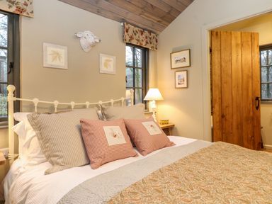 A bedroom with a bed pillows lamp wooden door and framed pictures at The Badger's Shack in Garnett Bridge Longsleddale Near Kendal