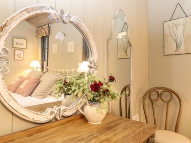 A wooden table with a floral vase and two mirrors above a wooden chair at The Badgers Shack in Garnett Bridge Longsleddale near Kendal