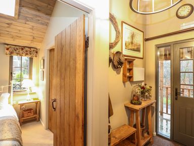 A bedroom with wooden door and nightstand next to an entryway with a wooden bench and table at The Badger's Shack in Garnett Bridge Longsleddale Near Kendal
