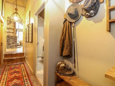 A hallway with a red patterned runner rug wooden floor coats hiking boots and hats on hooks at The Badger's Shack in Garnett Bridge Longsleddale Near Kendal