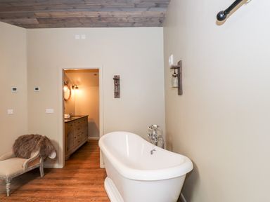A bathroom with a freestanding bathtub a chaise lounge and a vanity visible through a doorway at The Hare's Shack in Garnett Bridge Longsleddale Near Kendal