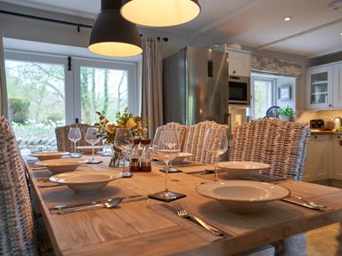 A dining table set with bowls wine glasses cutlery and a flower centerpiece in a kitchen at The Old Water Mill in Kendal