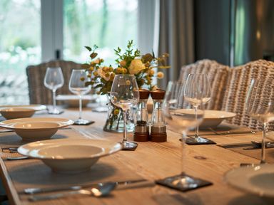 A dining table set with bowls wine glasses salt and pepper shakers and a flower arrangement at The Old Water Mill in Kendal