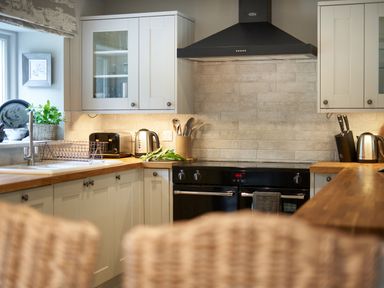 A kitchen with white cabinets wooden countertops black oven and extractor hood at The Old Water Mill in Kendal