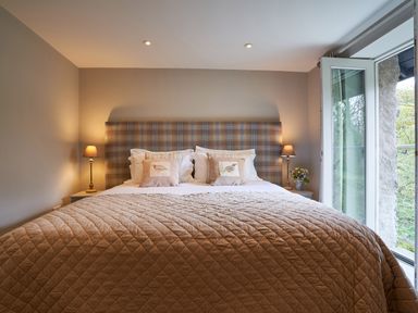 A bedroom with a large bed with pillows and lamps on bedside tables at The Old Water Mill in Kendal