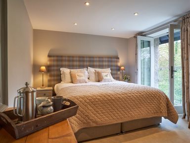 A bedroom with a double bed with plaid headboard and bedside lamps at The Old Water Mill in Kendal