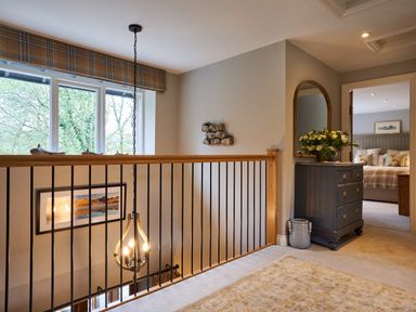 A hallway with a railing light fixture and dresser leading to a bedroom at The Old Water Mill in Kendal
