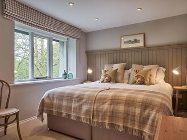 A bedroom with a bed that has rabbit pillows and a checkered blanket at The Old Water Mill in Kendal