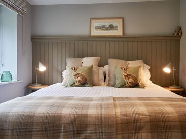 A bed with rabbit cushions and lamps on bedside tables at The Old Water Mill in Kendal